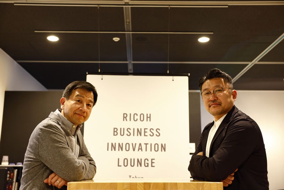 パノラマティクス主宰・齋藤精一氏(右)と、リコーフューチャーズビジネスユニット プレジデントの入佐孝宏氏(左)。対談は、リコーの価値共創スペース「RICOH BUSINESS INNOVATION LOUNGE Tokyo」で実施した。